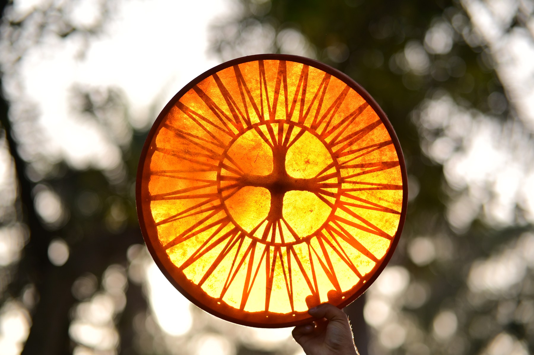 Orange drum held against sunlight, showing the radial lacing through its surface